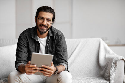 ein Mann sitzt auf einer Couch mit einem Tablet